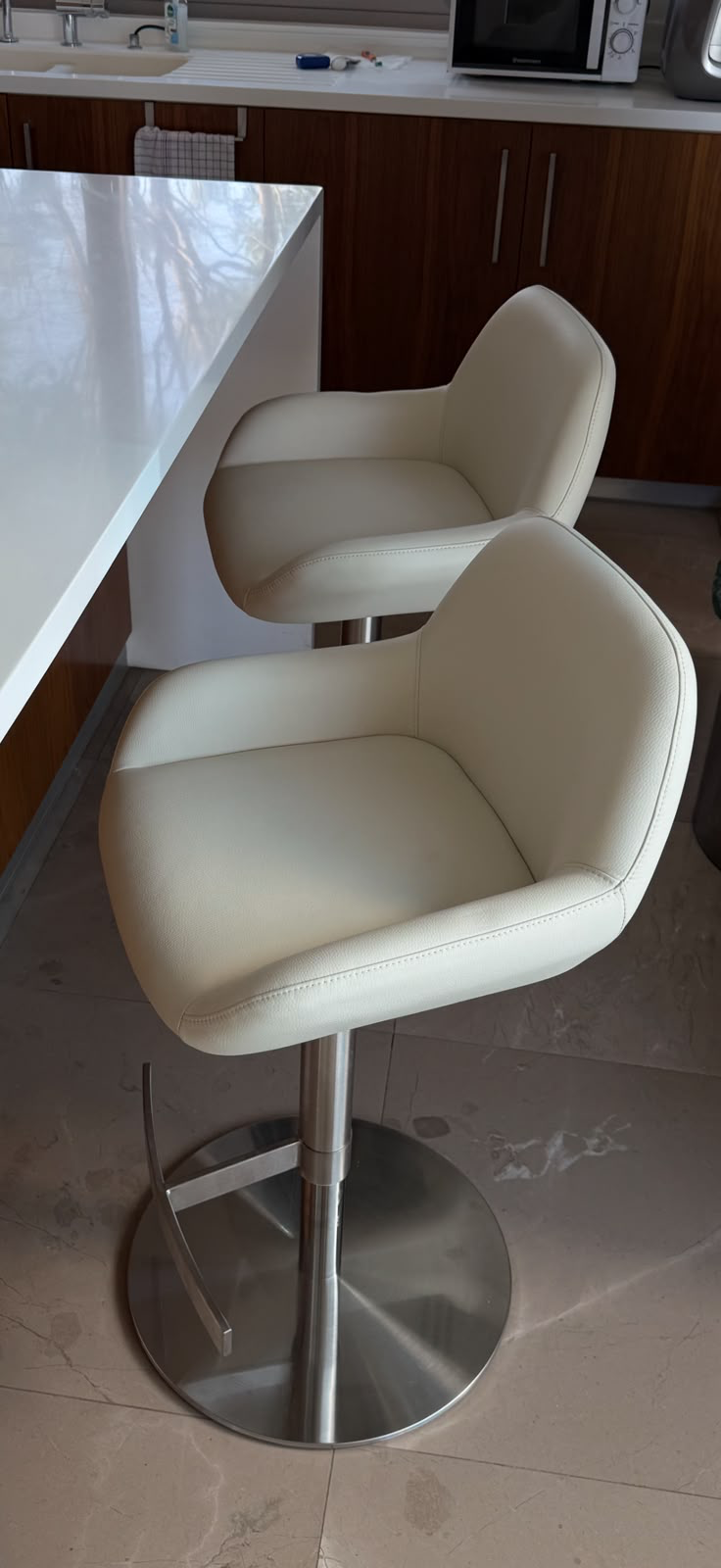 Cream leather adjustable bar stools at a white kitchen island