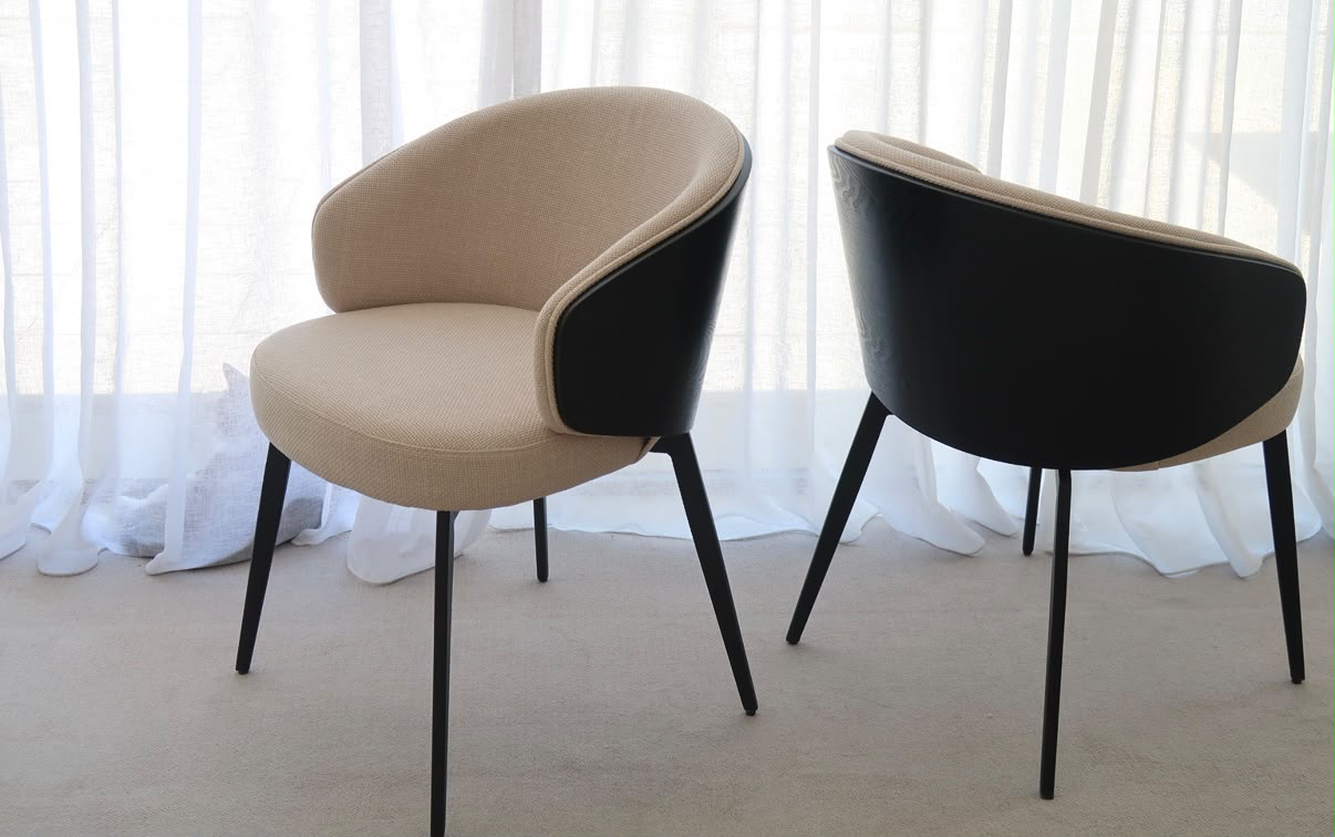 Two curved dining chairs in oatmeal fabric with black leather backs